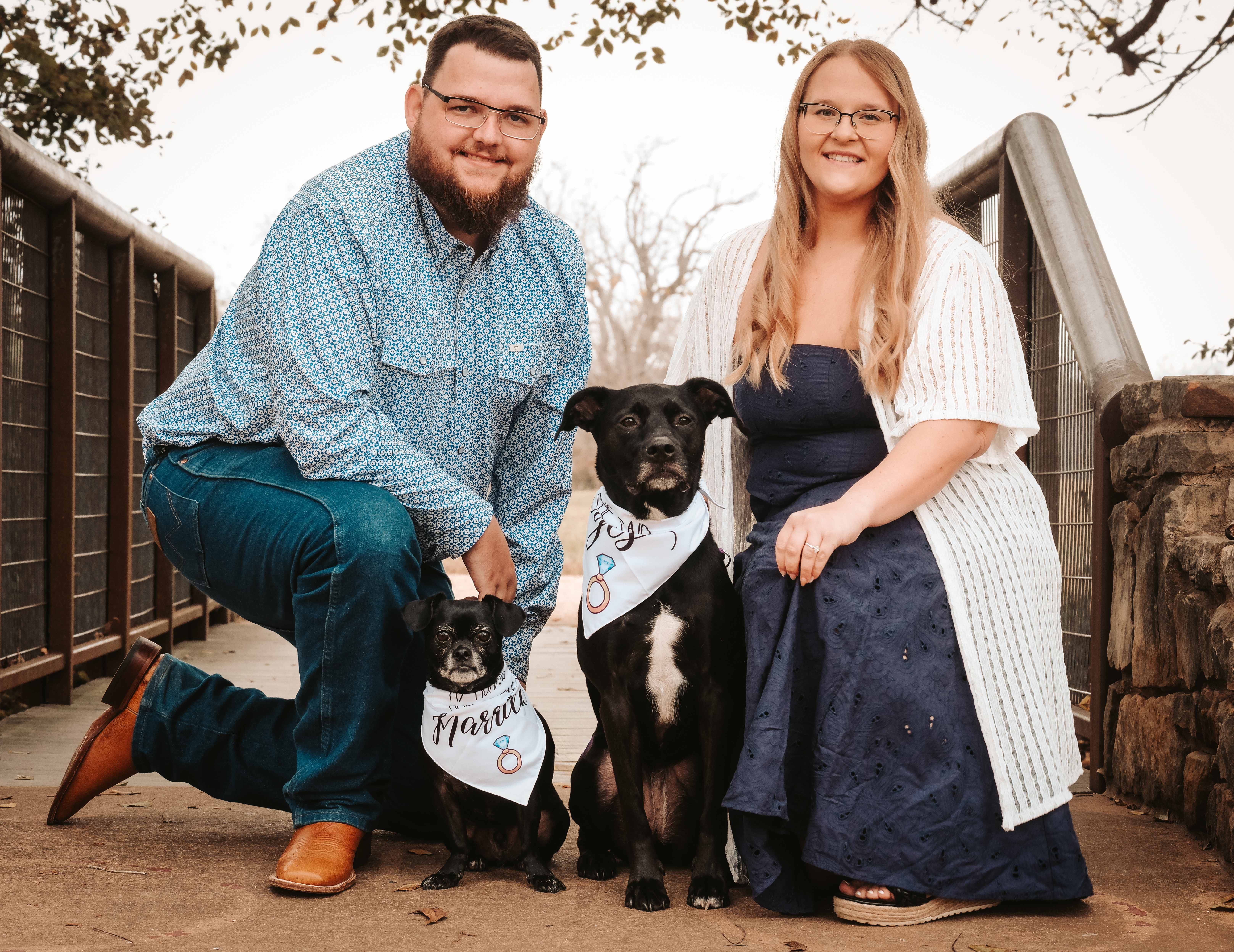 Jonathan and Shelby with their two dogs bandit a black chug and violet a black lab mix on a bridge.